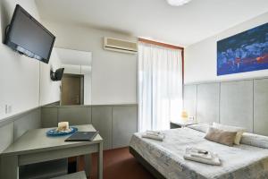 a bedroom with a bed and a desk and a television at Hotel Europa in Grado