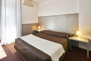 een slaapkamer met een bed en een bureau met 2 lampen bij Hotel Europa in Grado