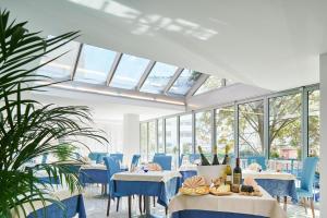 jadalnia ze stołami, niebieskimi krzesłami i oknami w obiekcie Hotel Europa w Grado