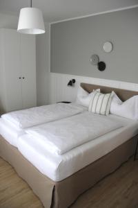 1 cama grande con sábanas y almohadas blancas en Strandhuus Norddeich, en Norddeich