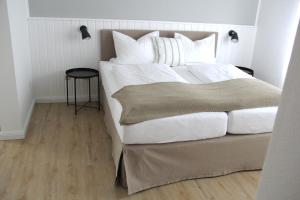 - une chambre dotée d'un grand lit avec des draps et des oreillers blancs dans l'établissement Strandhuus Norddeich, à Norddeich
