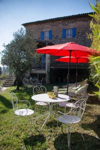 a table and chairs with a red umbrella at Chambres d'Hôtes et Gîtes Le Mas Bleu & Spa Resort in Rosières