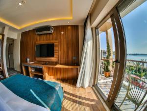 a room with a bed and a television and a balcony at DİAMOND LİMAN HOTEL in Bartın