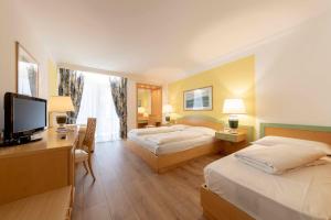 a hotel room with two beds and a television at Business Resort Parkhotel Werth in Bolzano