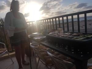a woman standing on a balcony next to a grill at Vista Oceano - Boa Vista Island in Sal Rei