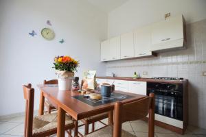 una cucina con tavolo in legno, sedie e piano cottura di Villa Giusy a Marina di Camerota