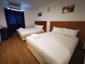 a bedroom with two beds and a desk and a window at Amanjaya Hotel in Sungai Petani