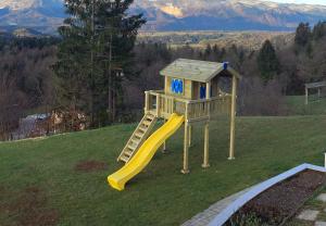 a playground with a yellow slide on a hill at Apartma Sonce Balkonce in Tržič