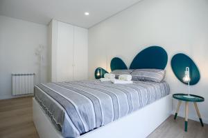 a bedroom with a large bed with a blue headboard at Pajaro Residence in Figueira da Foz