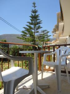 a table and chairs on a balcony with a pine tree at Mario Rooms in Vasiliki