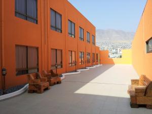 un couloir vide d'un bâtiment orange avec des bancs dans l'établissement Hotel Astore Suites, à Antofagasta