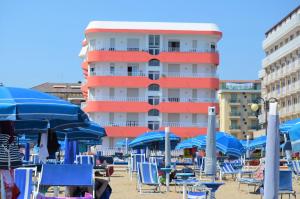 a building on the beach with chairs and umbrellas at Residence Apollo Immobiliare Pacella in Lido di Jesolo