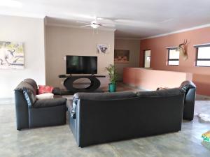 uma sala de estar com 2 sofás e uma televisão de ecrã plano em Hazyview Bogarts Villa em Hazyview