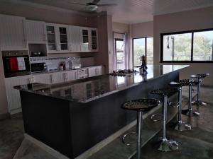 a kitchen with a black counter and bar stools at Hazyview Bogarts Villa in Hazyview