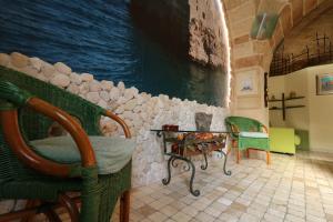 Zimmer mit Stühlen, einem Tisch und einer Wand in der Unterkunft Mulberry House in Polignano a Mare