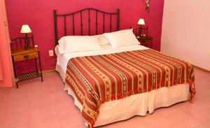 1 dormitorio con 1 cama grande y pared roja en Alquimia Posada en Guichón