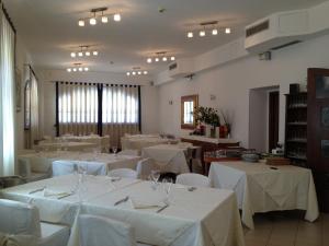 a large room with white tables and chairs with white table linen at La Vela in Viadana