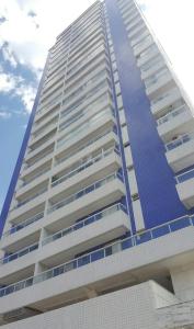 un edificio alto de color blanco con balcones azules en Lindo apartamento bairro Aviação, en Praia Grande