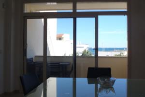 uma sala de jantar com uma mesa de vidro e uma janela em Appartamento a due passi dal mare em Torre Lapillo