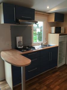 a kitchen with black cabinets and a wooden table at Camping les Palmiers in La Trinité-sur-Mer