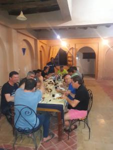 Un groupe de personnes assises à une table en train de manger dans l'établissement Amerdoul, à Icht