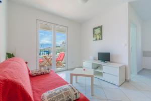 a living room with a red couch and a television at Beachfront Apartments Villa Šiša in Primošten