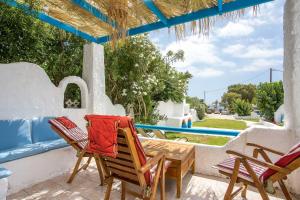 a patio with chairs and a table and a pool at Faliraki Blue Villas in Faliraki