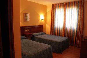 a hotel room with two beds and a window at Hostal Tio Pepe II in Bembibre