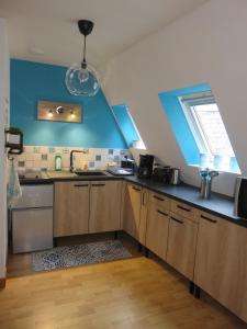- une cuisine avec un évier et un mur bleu dans l'établissement Grand appartement chaleureux, à Thouars