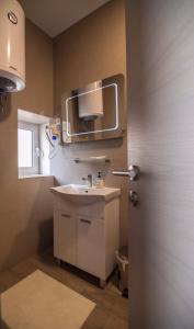 a bathroom with a sink and a tv on the wall at Apartmani MG in Trebinje