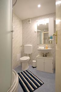 een badkamer met een wastafel, een toilet en een spiegel bij Golden Creek Amazing Sea Views Apartment in Dubrovnik