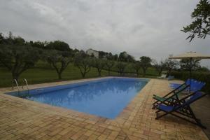 a swimming pool with two chairs and an umbrella at casa Nenella in Corridonia