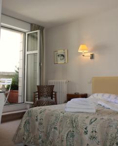 1 dormitorio con cama, ventana y silla en Hôtel Maïtagaria en Biarritz