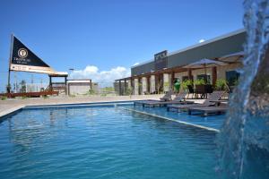 a swimming pool with chairs and a water fountain at Tropical Mar Hotel in Aracaju