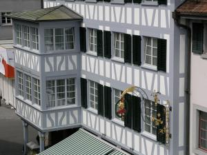 a white building with green shutters and a balcony at Hotel Restaurant zum goldenen Kopf in Bülach