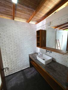 bagno con lavandino e parete di mattoni bianchi di White Sands Beach Resort Lembeh a Bitung