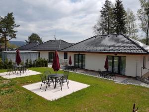 a house with tables and chairs in the yard at Slope Apartments Lipno in Lipno nad Vltavou
