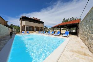 a swimming pool with chairs and a house at Villa Magnolia in Privlaka