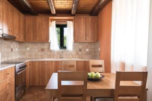 a kitchen with wooden cabinets and a bowl of fruit on a table at Villa Margarita in Anafonítria