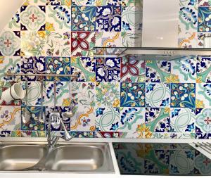 a kitchen with a sink and a tile wall at Trifoglio Apartment in Maiori +31 photos