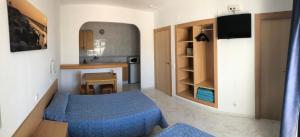 Habitación pequeña con cama azul y cocina en Apartamentos Playa Sol, en Es Canar