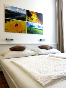 1 dormitorio con 2 camas blancas con pinturas en la pared en KIBI Rooms self check-in en Viena