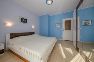 een slaapkamer met een wit bed en blauwe muren bij Apartment Marina in Rab