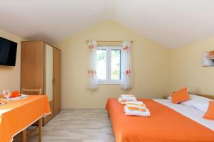 a bedroom with an orange bed with towels on it at Orange studio Eni in Hvar