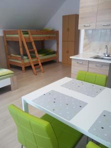 een keuken met een tafel en groene stoelen en een stapelbed bij Elza Vendégház in Sárospatak