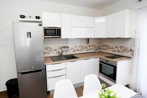 La cuisine est équipée de placards blancs et d'un réfrigérateur en acier inoxydable. dans l'établissement Apartments Romarin, à Supetar