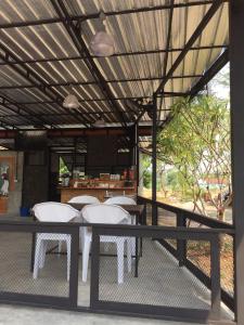 un patio con sillas blancas, una mesa y una barra en Happy Resort Bandung, en Ban Dung