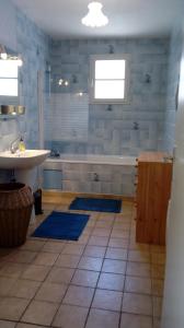La salle de bains est pourvue d'une baignoire, d'un lavabo et de tapis bleus. dans l'établissement Le 76, à Gamaches
