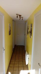 un couloir avec des toilettes dans une chambre aux murs jaunes dans l'établissement Le 76, à Gamaches