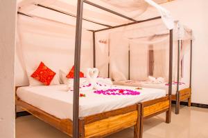 a bedroom with two beds with white sheets and flowers at East Beach Surf Resort in Arugam Bay